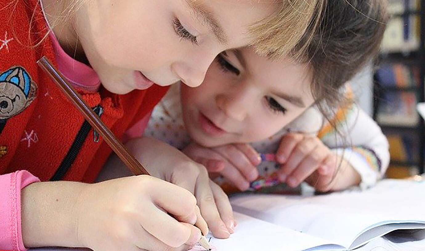 Two boys writing in a notebook